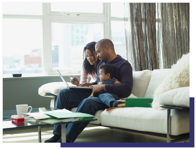 Two parents and a young child sit at home in front of a laptop