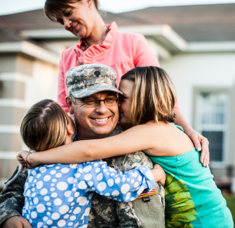 An Army soldier is hugged by his daughters and wife